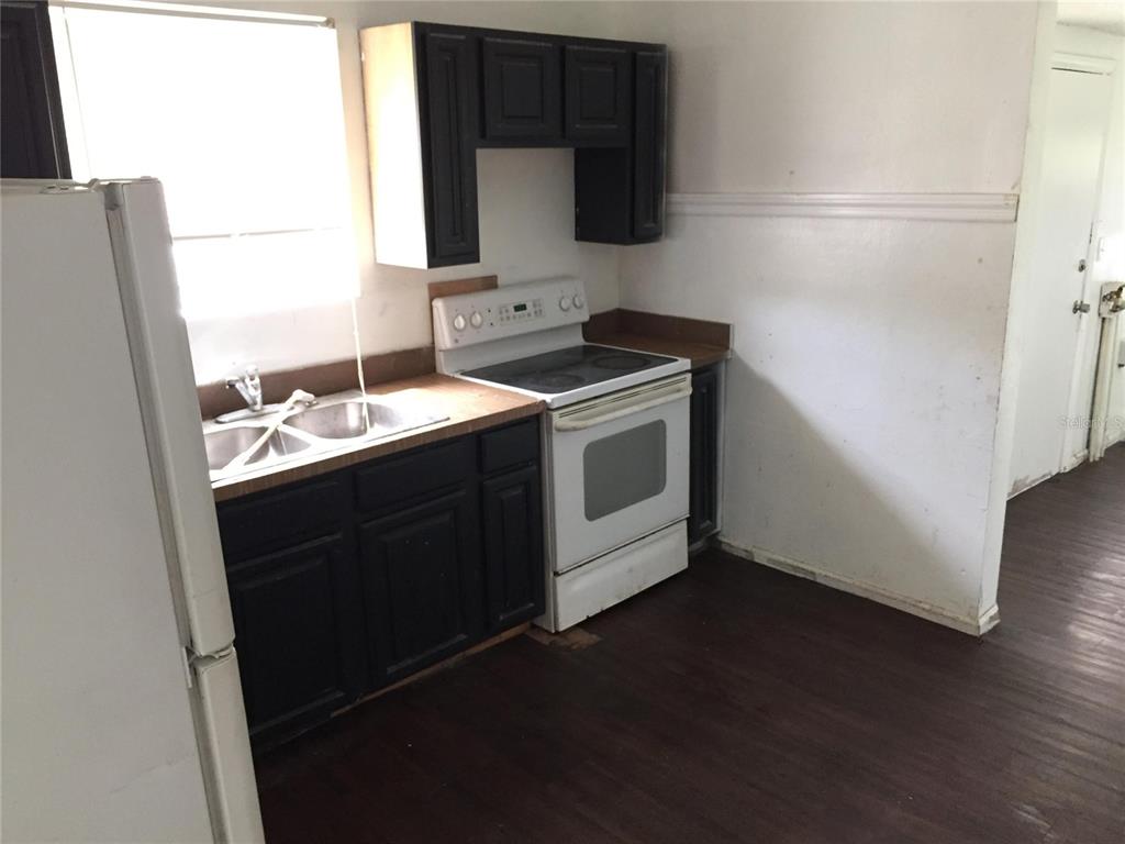 A kitchen features dark cabinets, a white stove, a double sink, and dark wood flooring — 1489 GROTHE STREET, JACKSONVILLE, FL