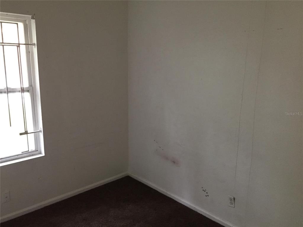 An empty room features white walls, dark carpeting, and a window with security bars — 1489 GROTHE STREET, JACKSONVILLE, FL