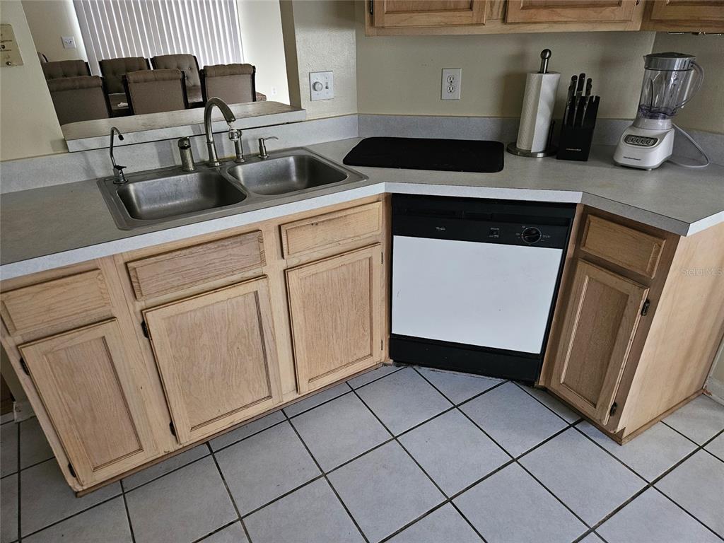 A kitchen features light wood cabinets, a double sink, a dishwasher, and tiled flooring — 8033 MACDOUGALL DRIVE E, JACKSONVILLE, FL