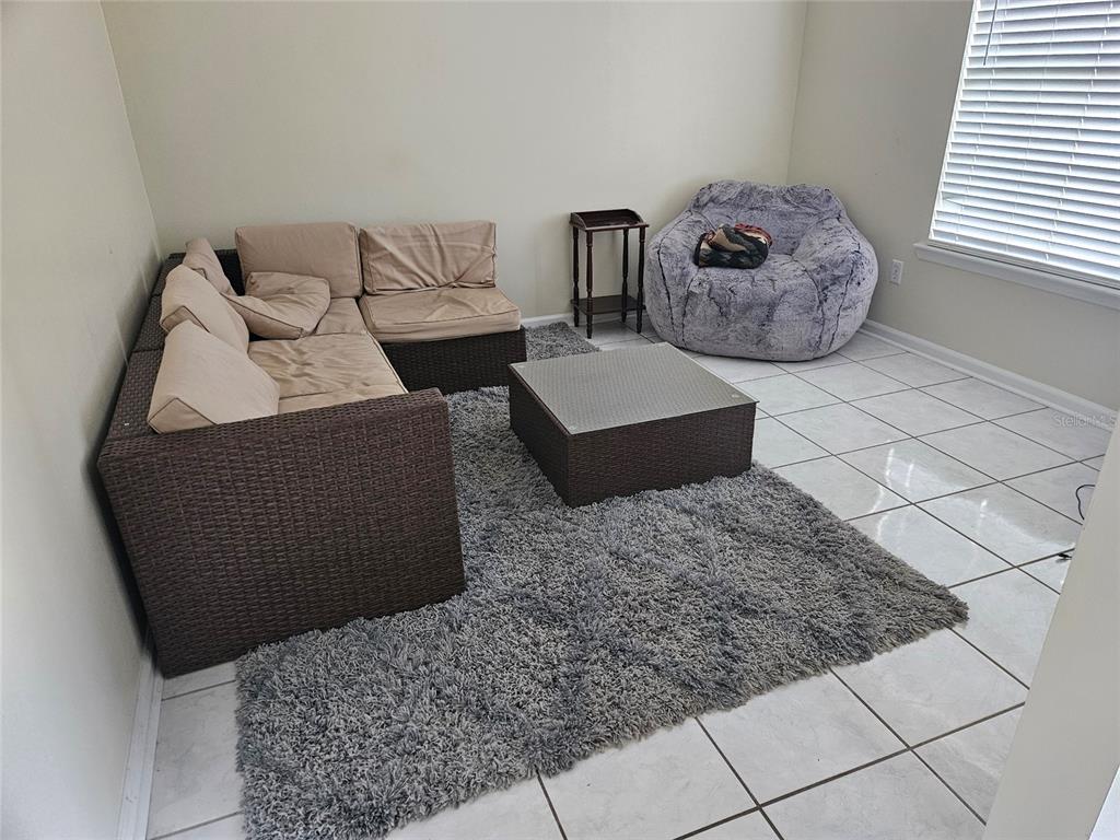 A living room features a wicker sectional sofa, a coffee table, and a gray beanbag chair — 8033 MACDOUGALL DRIVE E, JACKSONVILLE, FL