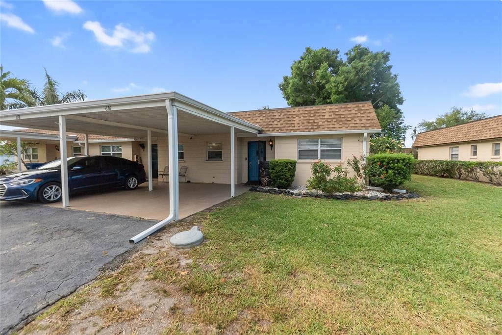A single-story house with a carport, a blue front door, and a grassy front yard — 676 PARK CIRCLE, BRADENTON, FL