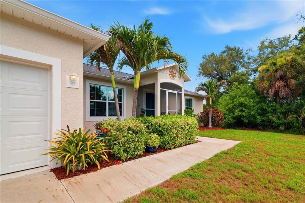 A single-story house exterior features a white garage door, a front porch, and palm trees — 6143 STURGIS STREET, ENGLEWOOD, FL