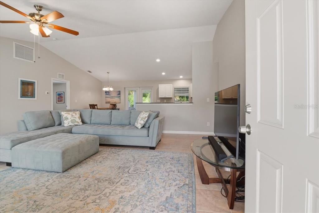 A living room features a light blue sectional sofa, a patterned rug, and a television — 6143 STURGIS STREET, ENGLEWOOD, FL
