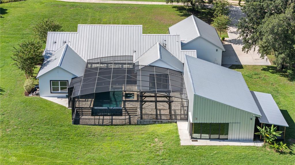 An aerial view of a white house with a metal roof and a screened pool enclosure — 19415 VILLA CITY ROAD, GROVELAND, FL