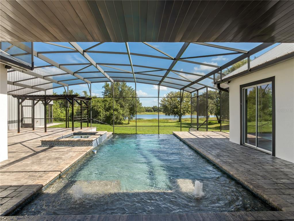 A screened-in patio features a swimming pool, a hot tub, and a view of water — 19415 VILLA CITY ROAD, GROVELAND, FL