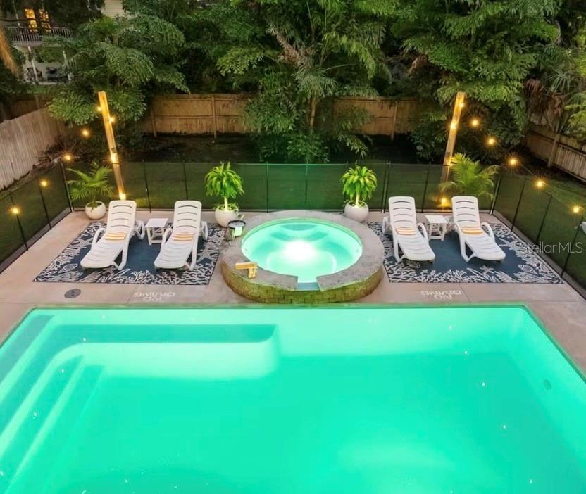An aerial view shows a rectangular swimming pool and a circular spa inside a fenced enclosure — 313 CRYSTAL BEACH AVENUE, CRYSTAL BEACH, FL