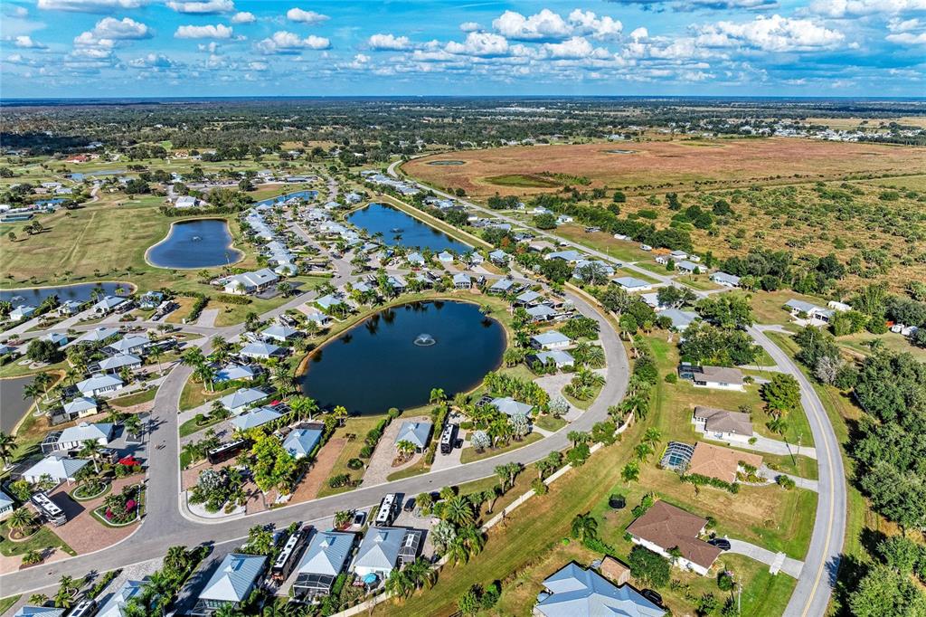 An aerial view shows a residential community with houses surrounding two ponds and a fountain — 8867 SW SAND CRANE CIRCLE LOT 21, ARCADIA, FL
