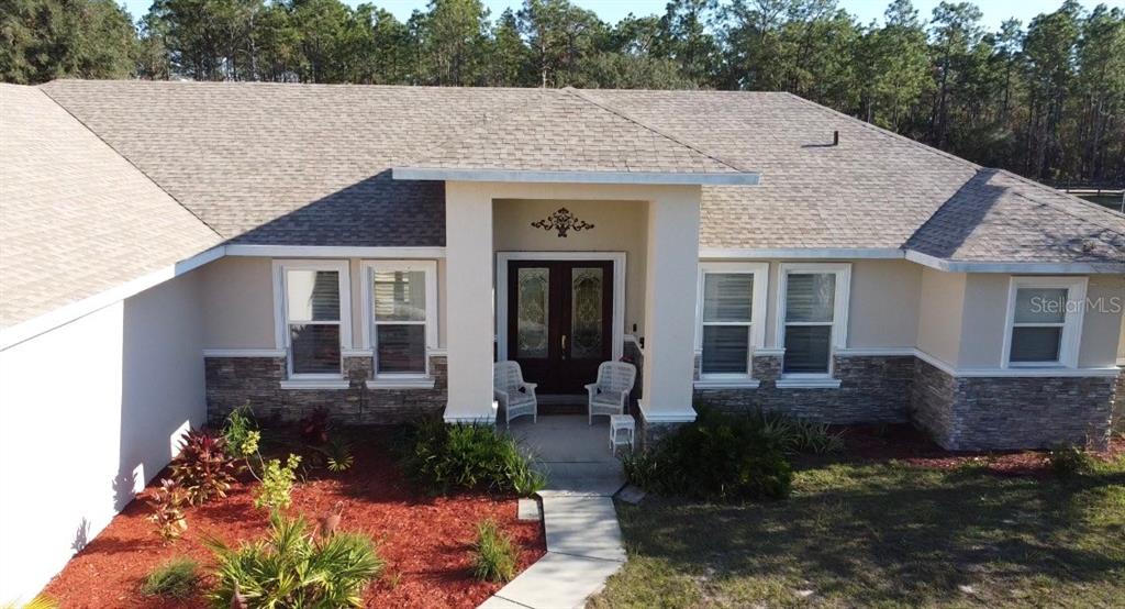 The exterior front entrance features a covered porch with two white chairs and double doors — 6081 W PELL PLACE, DUNNELLON, FL