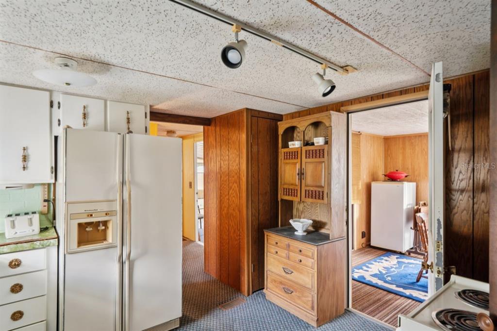 A kitchen with wood paneling, a white refrigerator, and a hutch leads into another room — 9310 KIOWA DR, NEW PORT RICHEY, FL