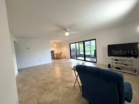 A living room with tile floors, a ceiling fan, and a sliding glass door to a patio — 11412 8TH ST N UNIT 1001, ST PETERSBURG, FL