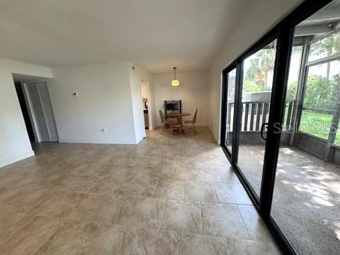 An open-concept living area features light-colored tile flooring and a sliding glass door to a lanai — 11412 8TH ST N UNIT 1001, ST PETERSBURG, FL
