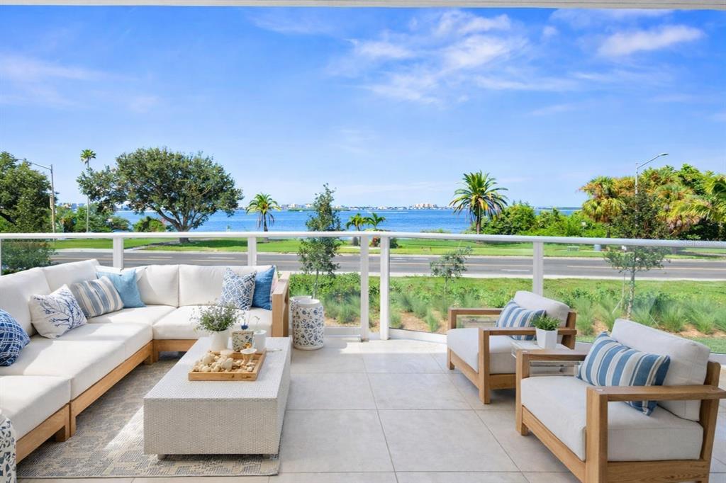An open-concept living and dining area features modern furniture, a wooden coffee table, and lighting — 1020 SUNSET POINT ROAD UNIT 103, CLEARWATER, FL