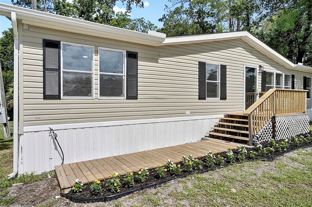 A single-story manufactured home with beige siding, black shutters, and a wooden front porch — 2318 COCONUT BOULEVARD, BUNNELL, FL