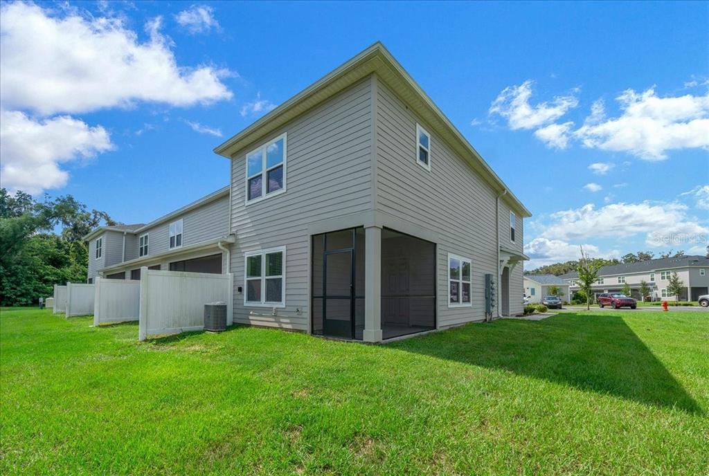 A two-story townhouse exterior with light gray siding, a screened-in porch, and a grassy yard — 3339 SE 37TH AVENUE ROAD, OCALA, FL