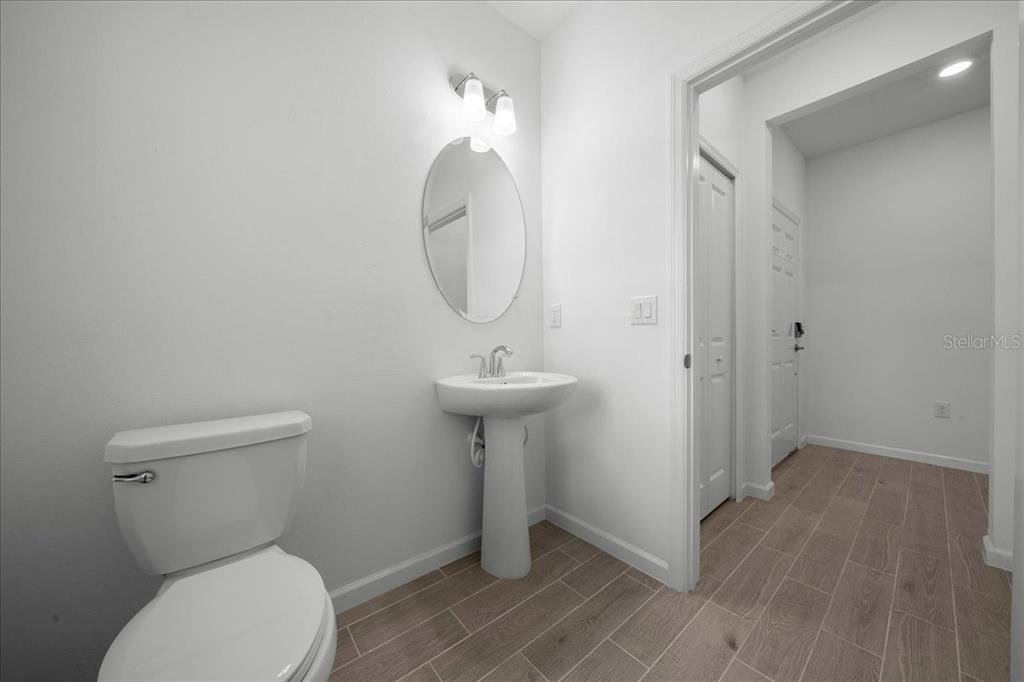 A half bathroom features a pedestal sink, a toilet, and light-colored tile flooring — 3339 SE 37TH AVENUE ROAD, OCALA, FL