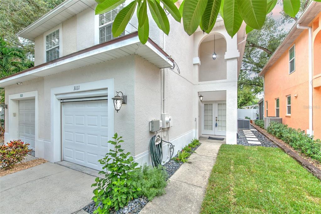 The exterior of a two-story townhouse features a garage, a front entrance, and a lawn — 3111 W SAN PEDRO STREET, TAMPA, FL