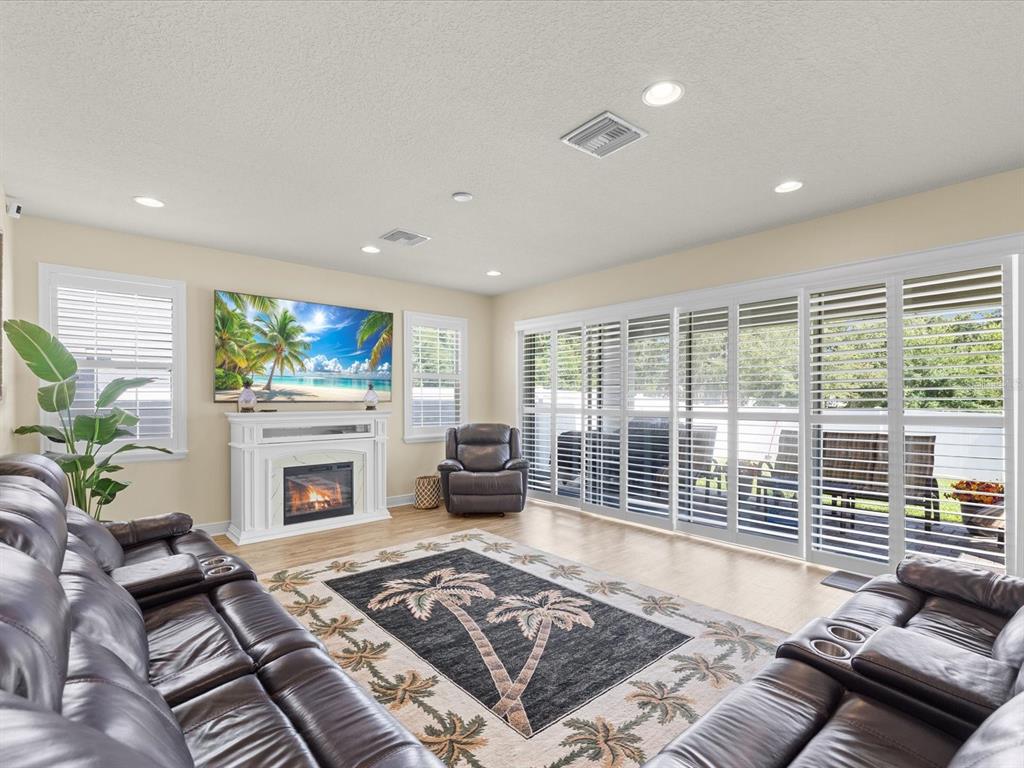A modern kitchen features white cabinets, a central island, stainless steel appliances, and wood flooring — 7117 PARK TREE DRIVE, TAMPA, FL