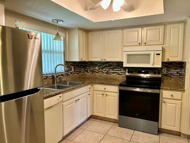 A kitchen features white cabinets, granite countertops, stainless steel appliances, and a tiled backsplash — 2529 OAKLEAF LANE UNIT 30C, CLEARWATER, FL