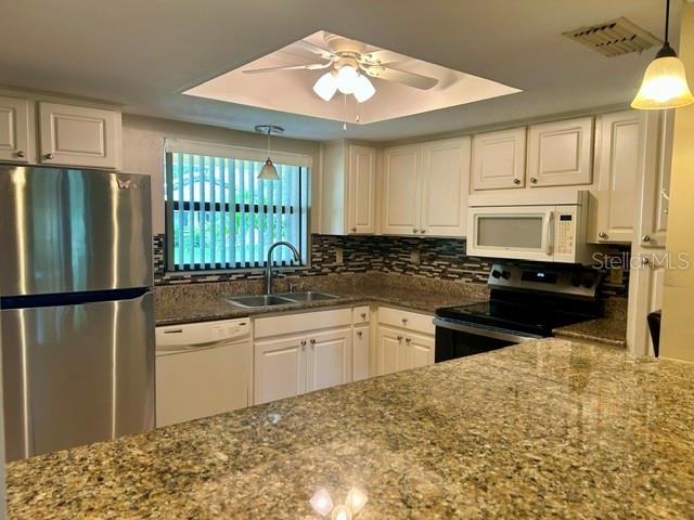 A kitchen features white cabinets, granite countertops, stainless steel appliances, and a ceiling fan — 2529 OAKLEAF LANE UNIT 30C, CLEARWATER, FL
