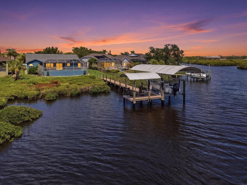 A blue single-story house with a two-car garage and palm trees at sunset — 4844 14TH AVENUE E, BRADENTON, FL