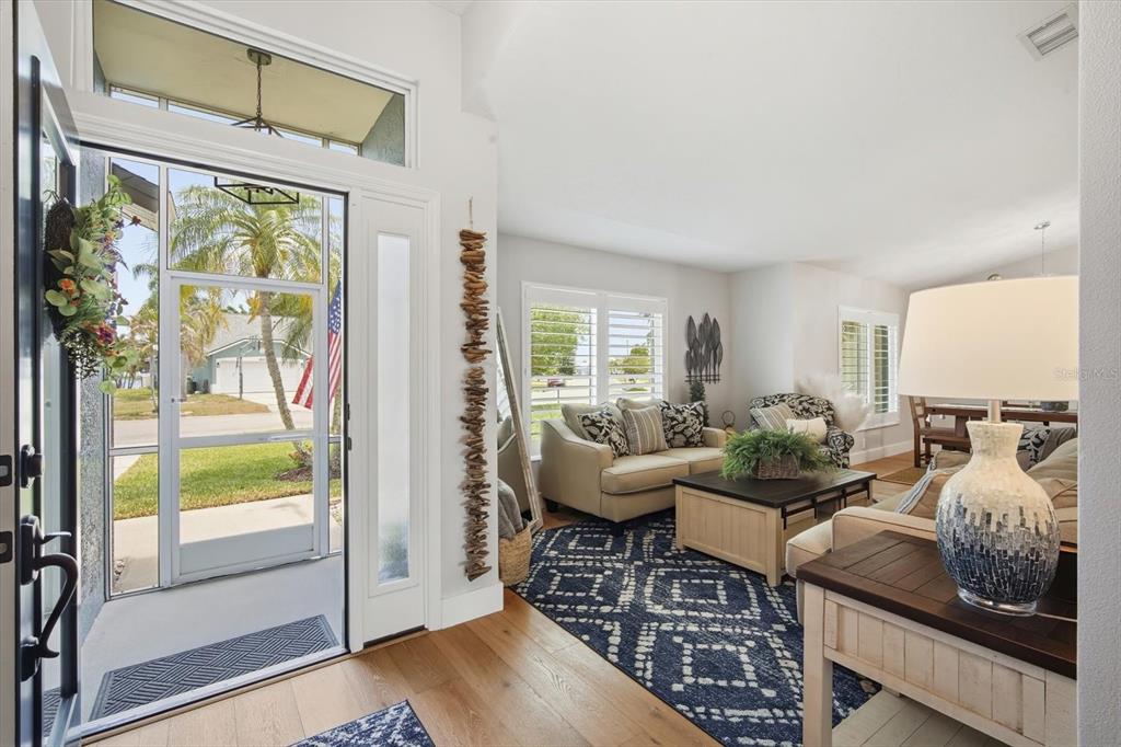 A bright entryway features two patterned chairs, a blue rug, and wall-mounted decorative art — 4844 14TH AVENUE E, BRADENTON, FL