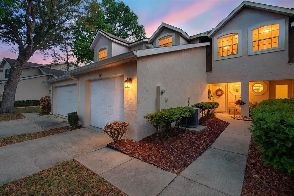 A beige two-story townhouse features a garage, a front walkway, and landscaped shrubbery — 525 LAKE BRIDGE DRIVE, ORMOND BEACH, FL