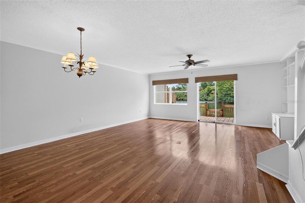 A kitchen with white cabinets and appliances opens into a living area with wood flooring — 525 LAKE BRIDGE DRIVE, ORMOND BEACH, FL