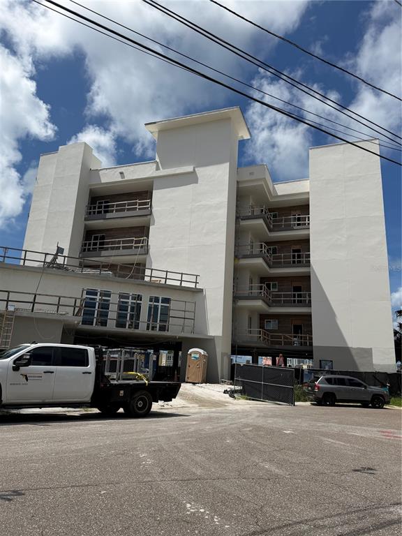 An aerial view shows a multi-story concrete apartment building under construction beside a waterway — 211 SKIFF POINT UNIT 3A, CLEARWATER, FL