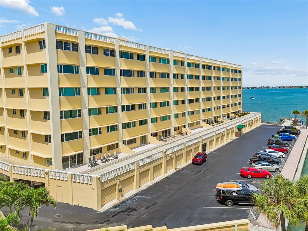 An aerial view shows a multi-story yellow apartment building with a parking lot beside water — 100 BLUFF VIEW DRIVE UNIT 509C, BELLEAIR BLUFFS, FL