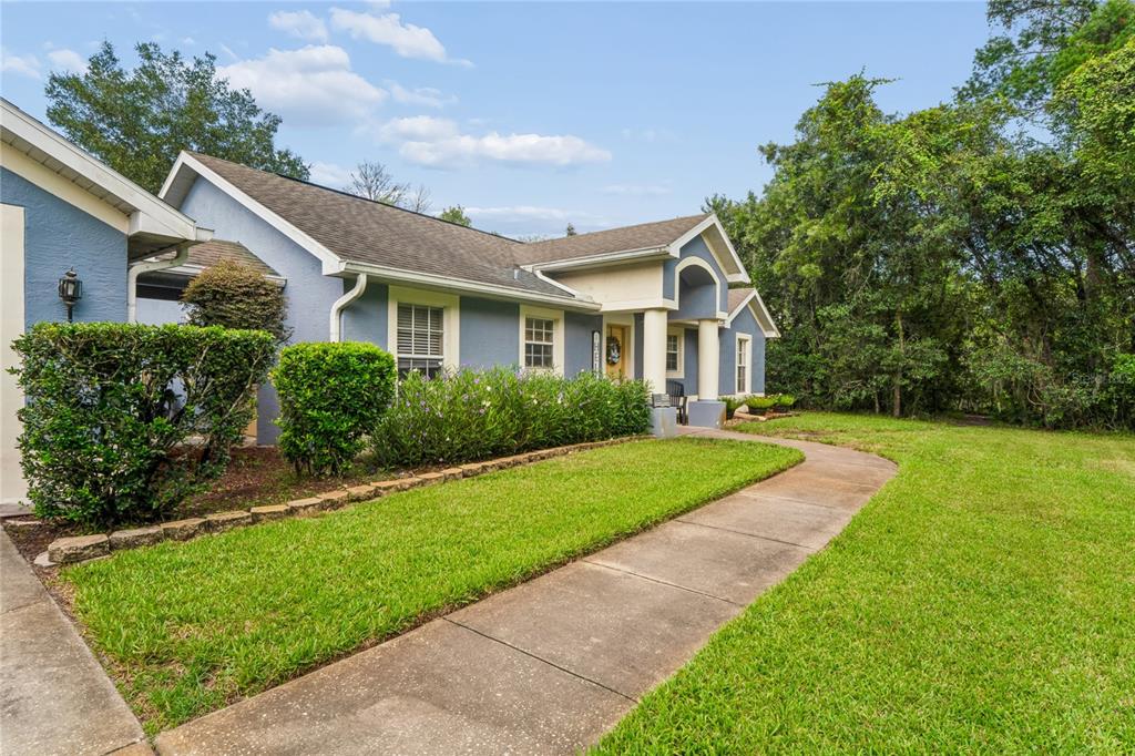 A blue house with a concrete walkway leading to the front entrance and landscaped yard — 10447 GRANNING LANE, NEW PORT RICHEY, FL