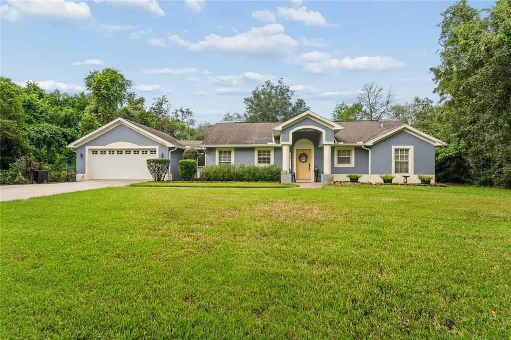 A single-story blue house with a two-car garage and a central arched entryway — 10447 GRANNING LANE, NEW PORT RICHEY, FL
