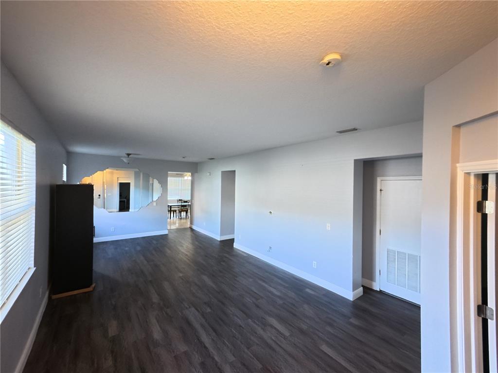 An open living area features gray walls, dark wood-look flooring, and a large decorative wall mirror — 1701 CHALKSAND WAY, RUSKIN, FL