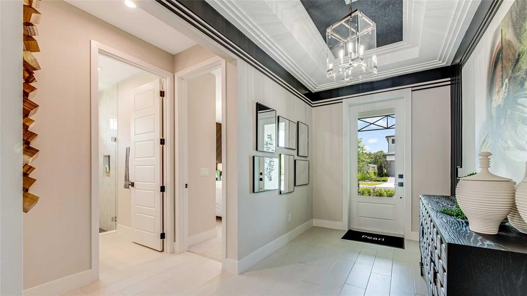 A bright entryway features a tray ceiling, a glass-paneled door, and light-colored tile flooring — 1242 CRESSWIND BOULEVARD, DELAND, FL