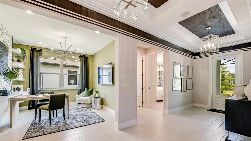 A home office with olive walls and a desk connects to a bright entryway foyer — 1242 CRESSWIND BOULEVARD, DELAND, FL