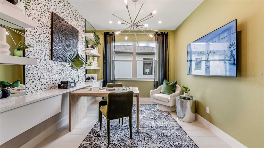 A home office features a desk, a swivel chair, a wall-mounted television, and patterned wallpaper — 1242 CRESSWIND BOULEVARD, DELAND, FL