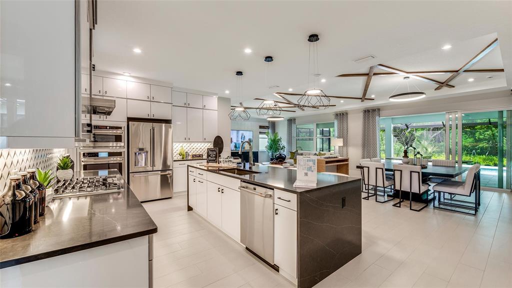 A modern kitchen features white cabinetry, a large dark island, and an open dining area — 1242 CRESSWIND BOULEVARD, DELAND, FL