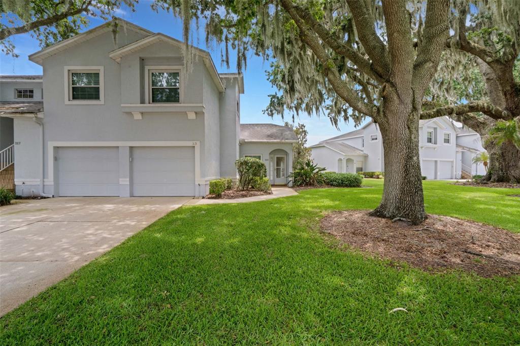 A two-story light gray townhouse with a two-car garage and a large oak tree — 313 EAGLE RIDGE DRIVE UNIT 313, DAVENPORT, FL