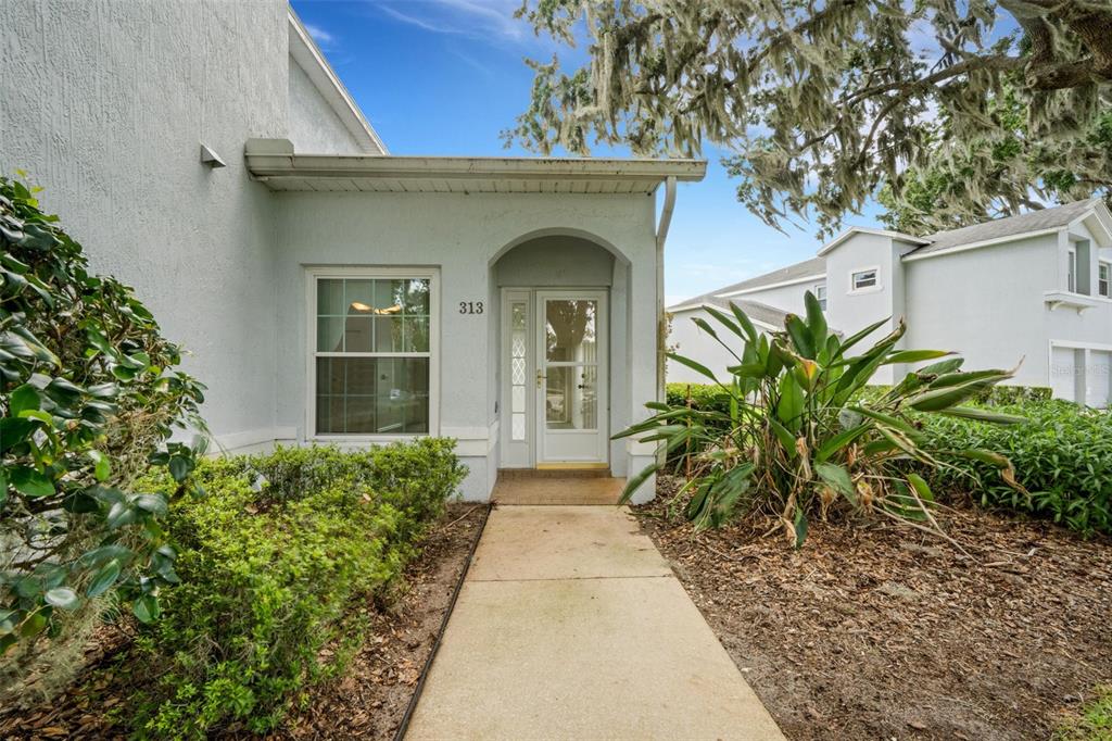 A concrete walkway leads to the front entrance of a light-colored residential building — 313 EAGLE RIDGE DRIVE UNIT 313, DAVENPORT, FL