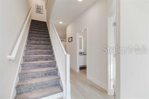 A carpeted staircase with a white railing leads to an upper floor in a hallway — 17102 BLESSING DRIVE, CLERMONT, FL
