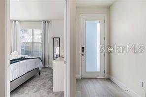 A view from a hallway looking into a bedroom with a bed and a door — 17102 BLESSING DRIVE, CLERMONT, FL