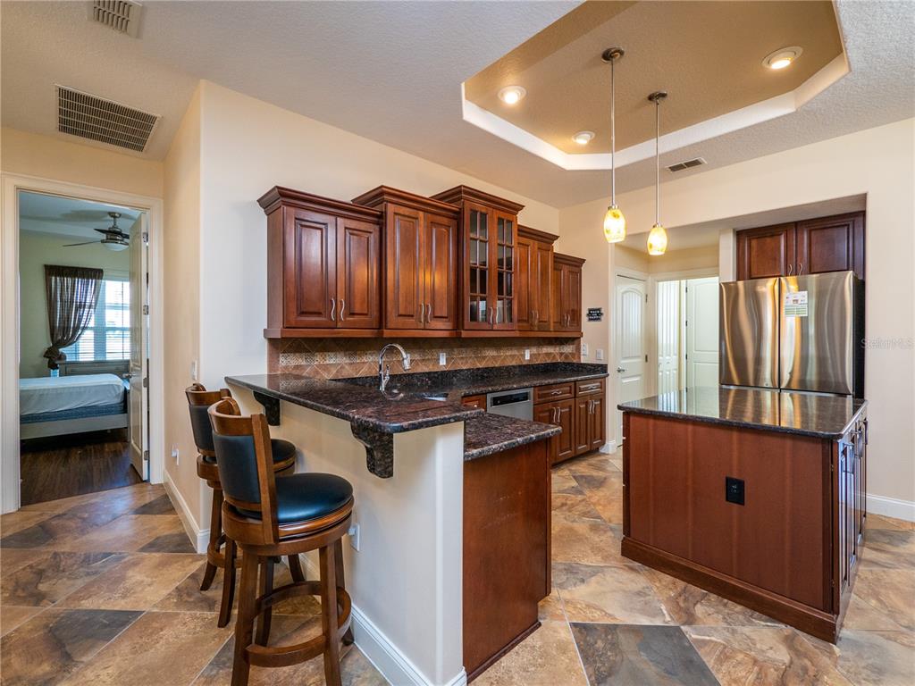A kitchen features dark wood cabinets, granite countertops, a breakfast bar, and tile flooring — 1719 SW 27TH PLACE, OCALA, FL