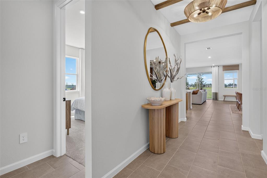 A hallway with tile flooring leads to an open living area featuring a wood-accented ceiling — 34902 FLOWER PATCH DRIVE, DADE CITY, FL