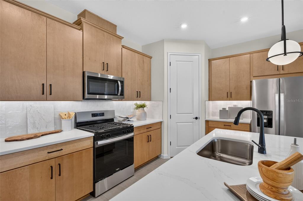 A kitchen with light wood cabinets, stainless steel appliances, white countertops, and a central island — 34902 FLOWER PATCH DRIVE, DADE CITY, FL