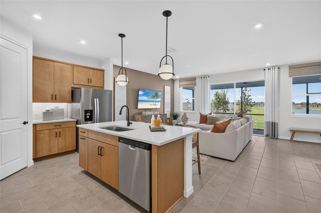 A modern kitchen with light wood cabinets and a white island overlooks a living area — 34902 FLOWER PATCH DRIVE, DADE CITY, FL