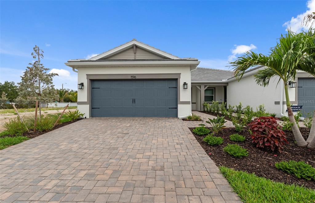 A single-story house with a gray garage door, a paved driveway, and landscaped front yard — 1596 TAVIRA PLACE, ENGLEWOOD, FL