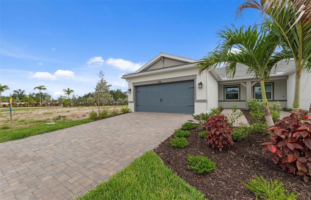 A single-story house with a gray garage, paver driveway, and landscaped front yard — 1596 TAVIRA PLACE, ENGLEWOOD, FL