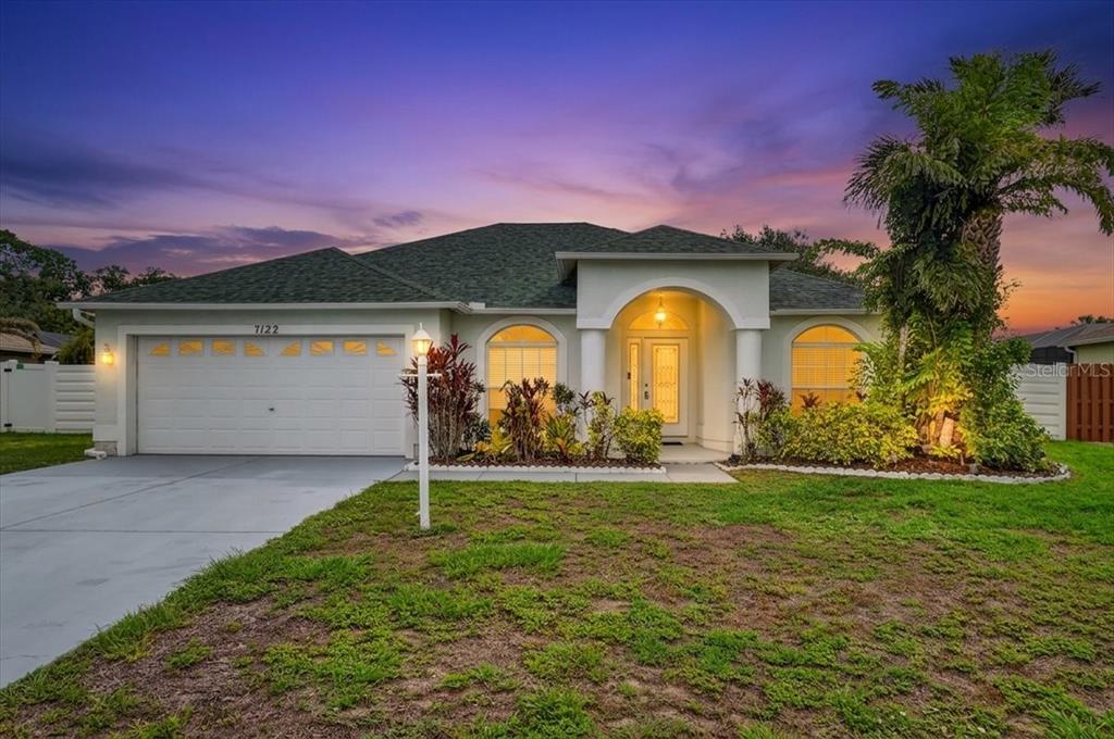 A single-story suburban house with a two-car garage, arched windows, and a covered entryway — 7122 87TH LANE E, PALMETTO, FL
