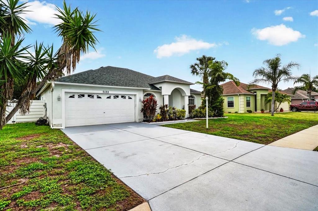 A single-story house with a white garage, arched entryway, and a concrete driveway — 7122 87TH LANE E, PALMETTO, FL