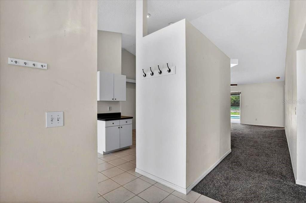 A view from a tiled entryway looking toward a kitchen and a carpeted living area — 7122 87TH LANE E, PALMETTO, FL