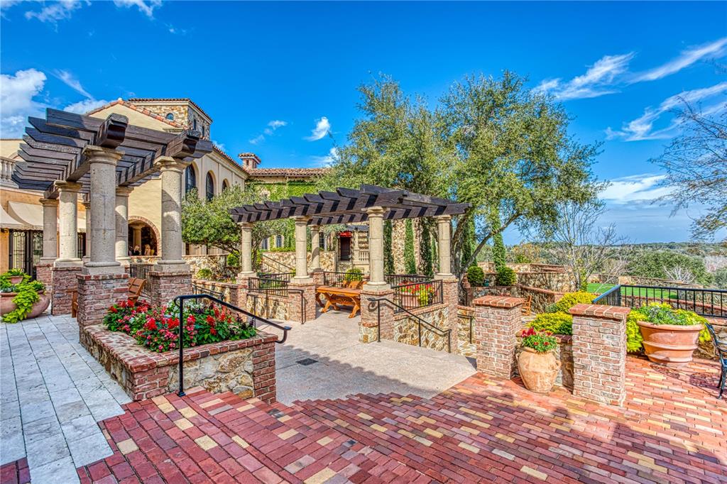 A stone patio features a wooden pergola, brick accents, and potted plants overlooking a landscape — 15942 PENDIO DRIVE, MONTVERDE, FL